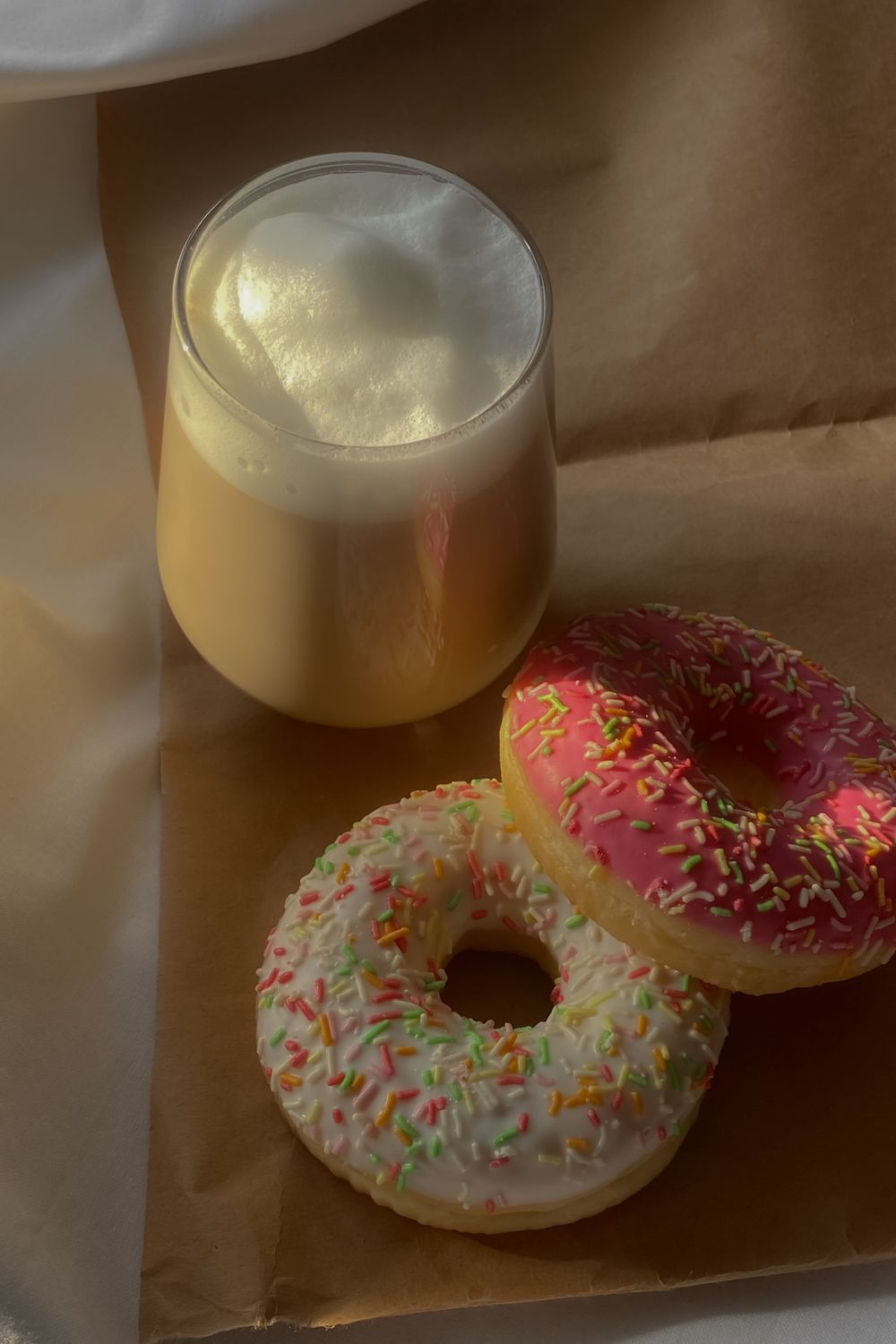 Iced coffee and two sprinkled donuts on a table, a typical afternoon sugar-and-caffeine snack