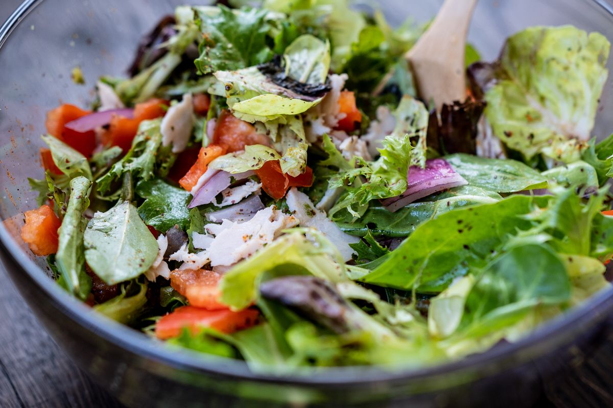 A glass bowl filled with a colorful fresh mixed vegetable salad on a light surface