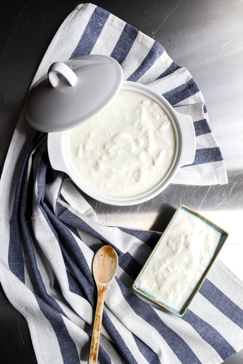 Homemade yogurt in a ceramic bowl on a striped cloth, seen from above
