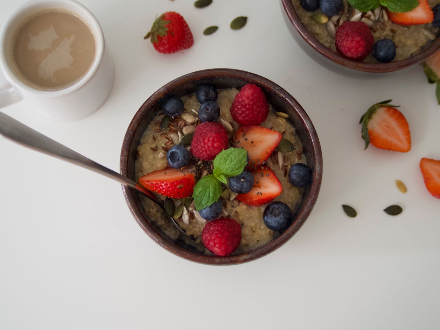A bowl of oatmeal topped with fresh blueberries, strawberries and raspberries on a wooden table