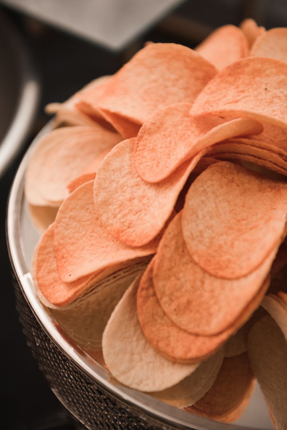 A bowl piled high with thin, crisp potato chips seen from close range