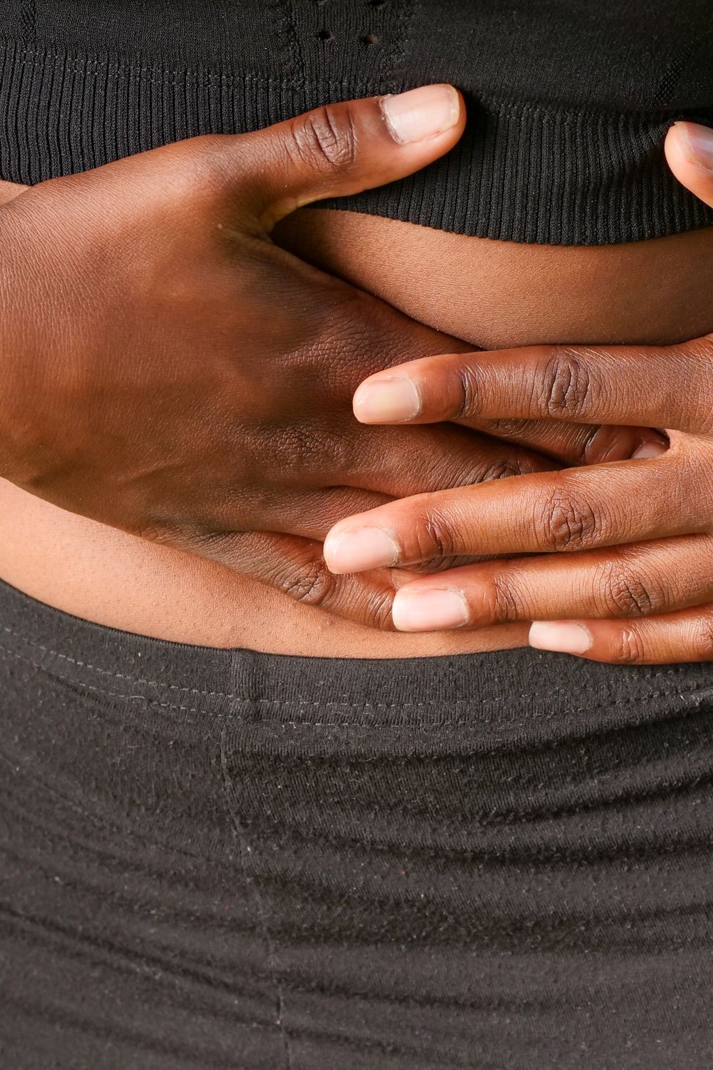 A person holding their hands over their stomach in mild discomfort