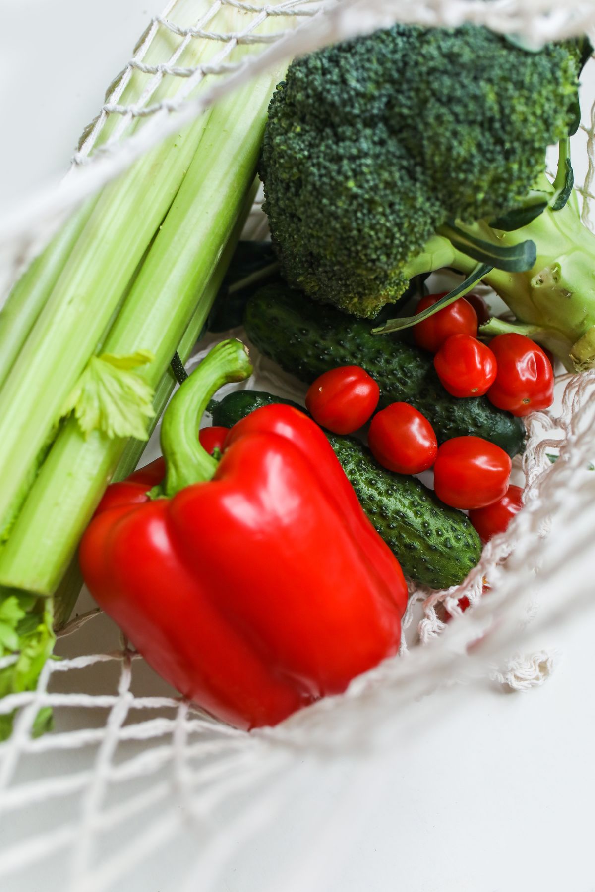Fresh broccoli, peppers and cucumbers in a net produce bag