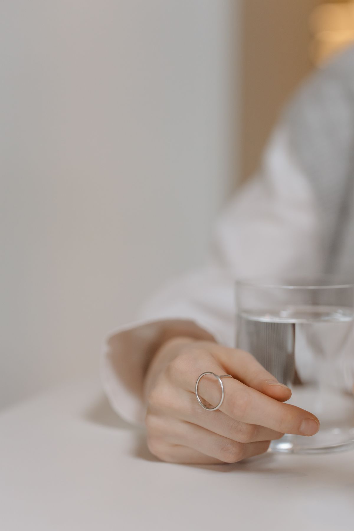 A hand reaching for a glass of water on a light table, minutes before a meal