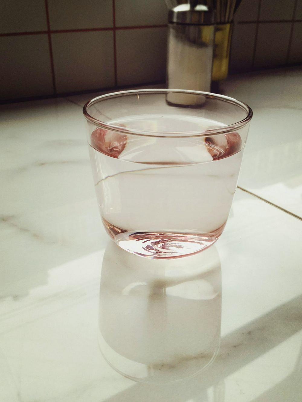 A full glass of water catching soft light on a kitchen counter